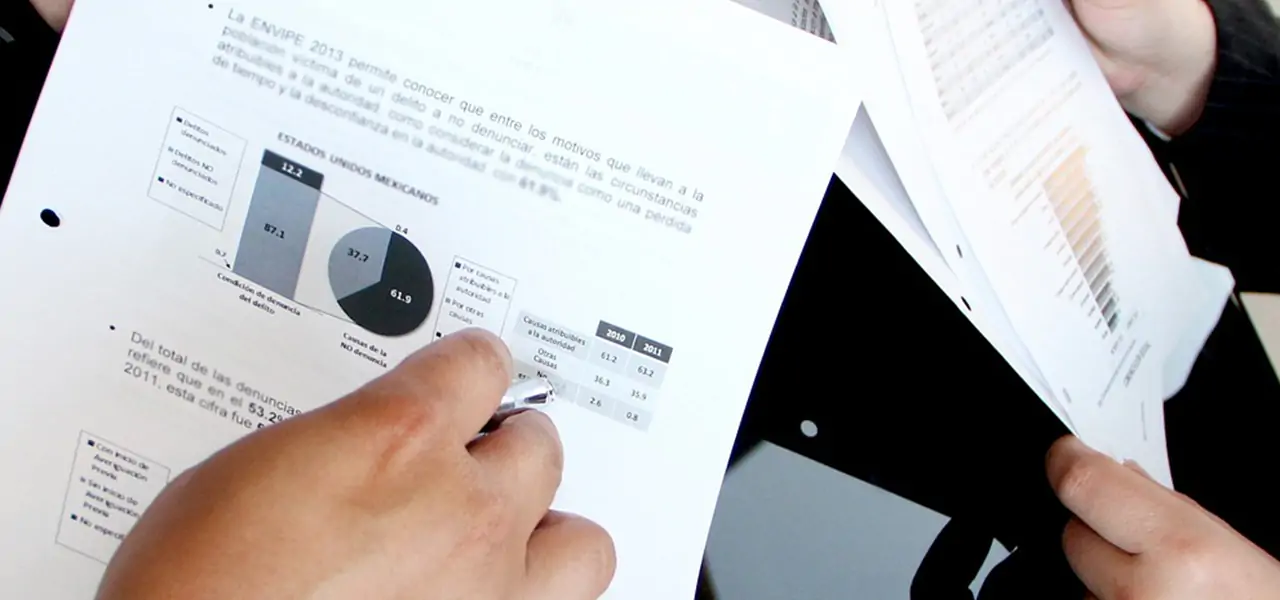 A man' shows data to other man by pointing to a data table.